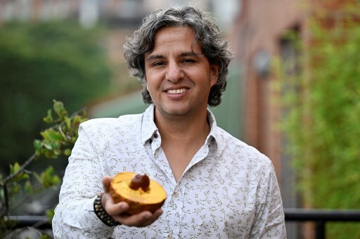 GIan Paolo Daguer, conhecido como 'senhor das frutas', sorri enquanto mostra para a câmera uma lúcuma, uma das frutas exóticas que integram seu projeto